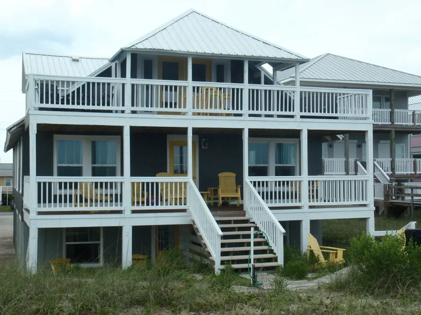 Beachfront building with white porches, central stairs and a lower-level patio