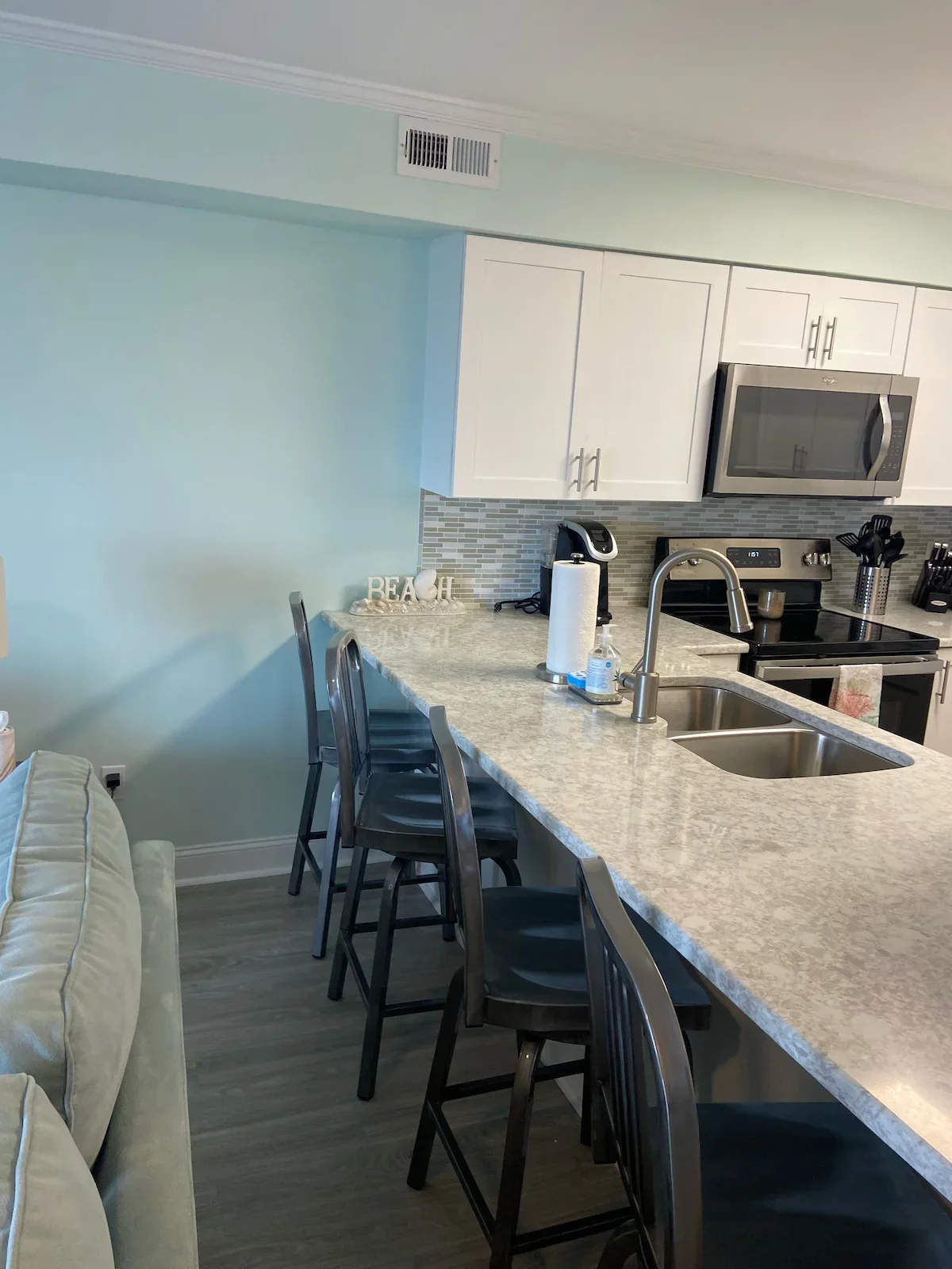 Breakfast stools beside a kitchen counter, sink and electric range