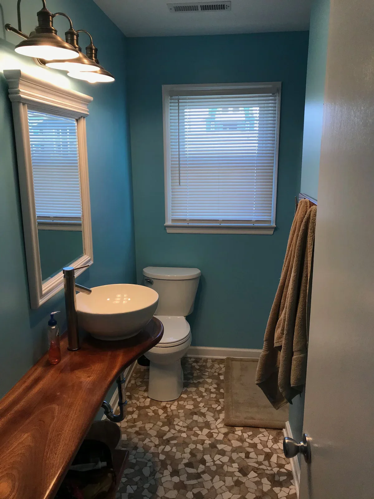Blue-walled bathroom with a vessel sink, toilet and window