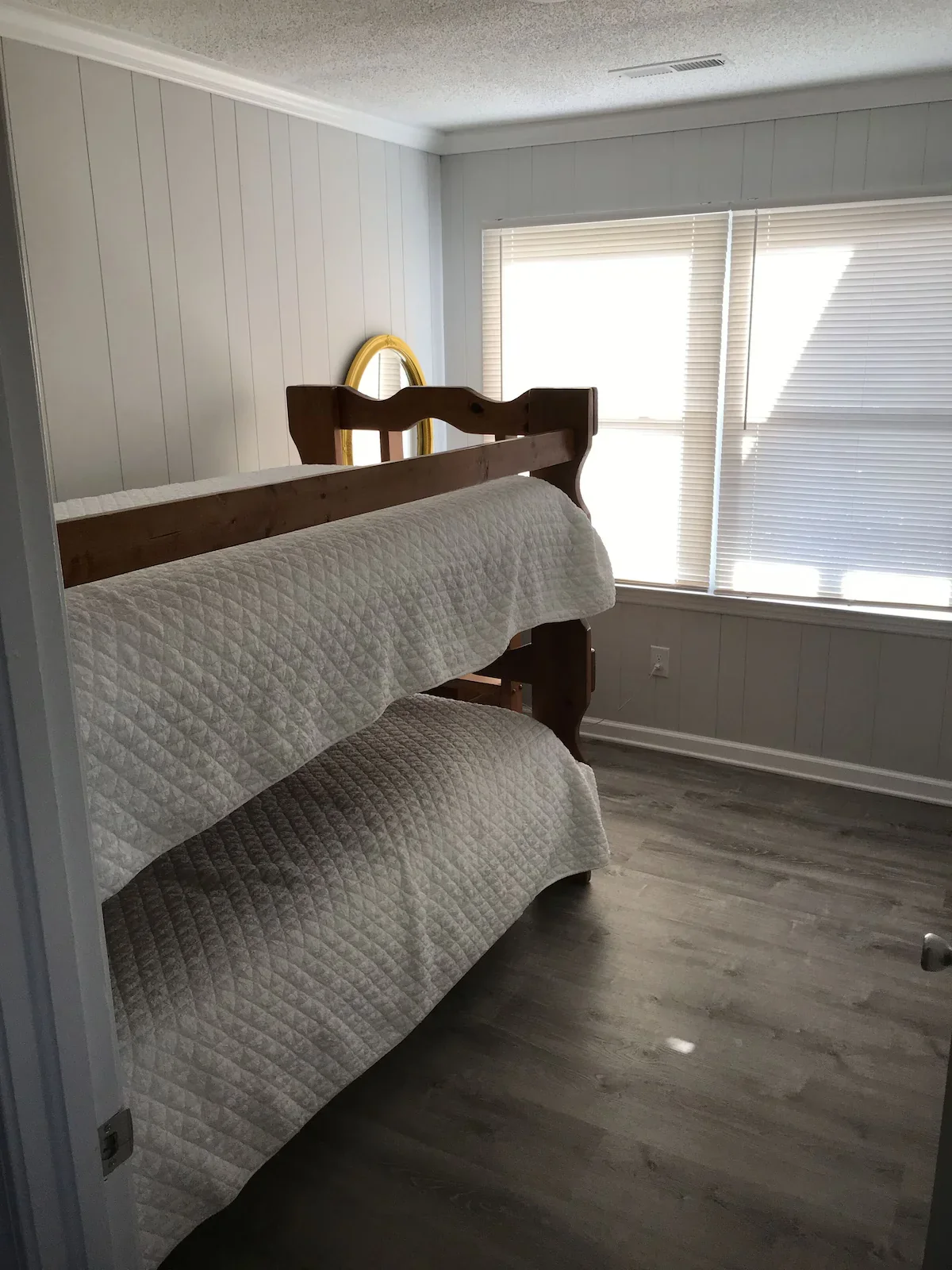 Wooden twin bunk beds beside a window in a separate bedroom