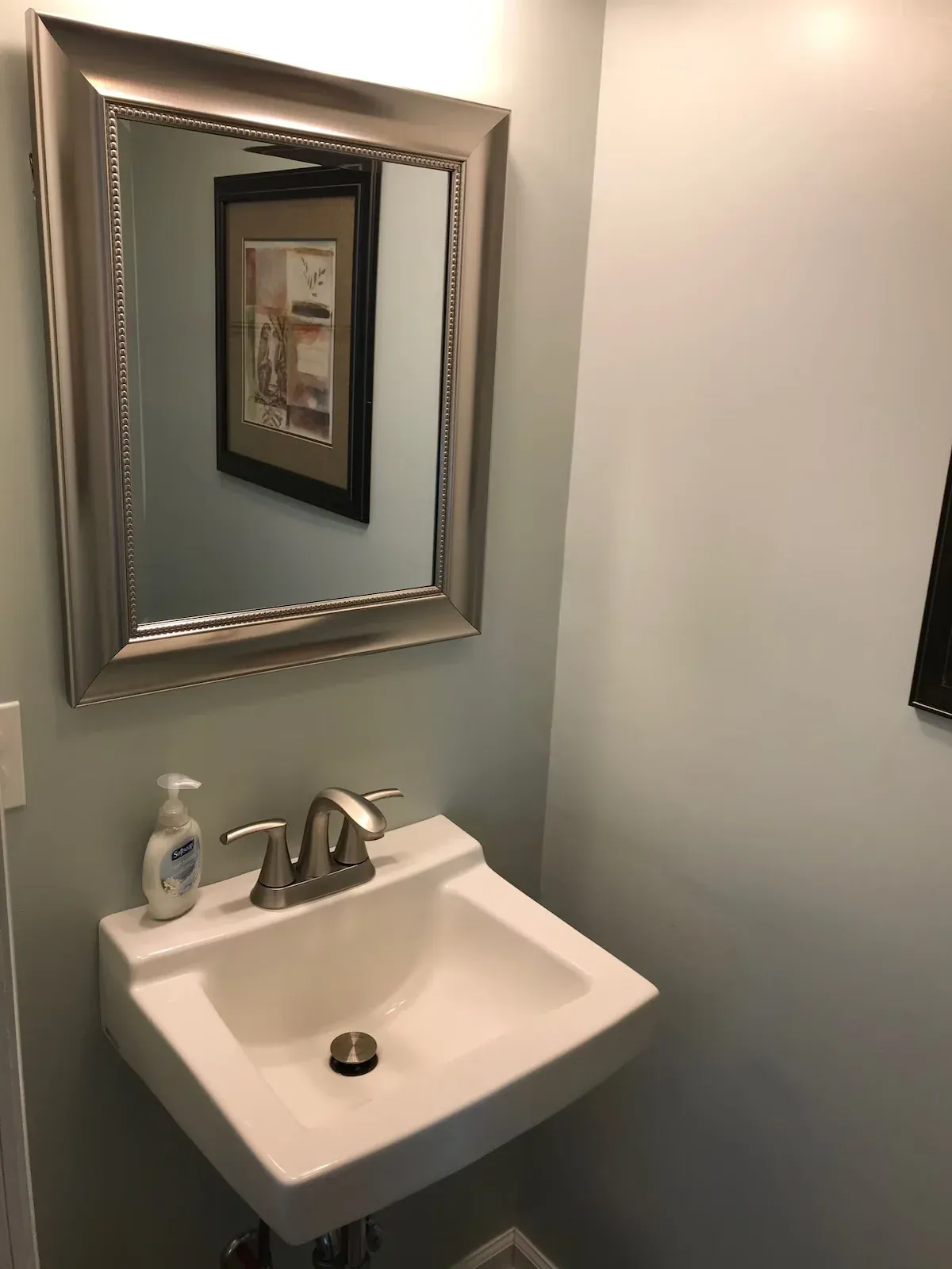 White sink and silver-framed mirror in the half bathroom